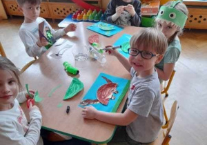 Dzieci malują diplodoki przy stoliku